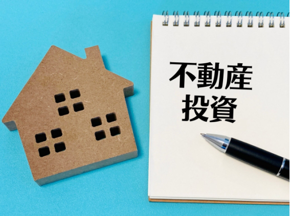 不動産投資を検討するイメージ（家の模型と「不動産投資」のノート）