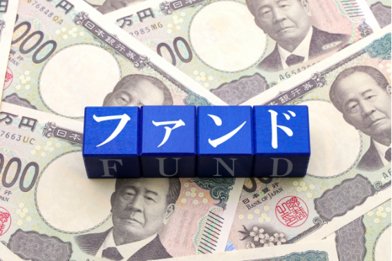 日本円の紙幣の上に並べられた「ファンド FUND」の文字ブロック。不動産クラウドファンディングをイメージ。
