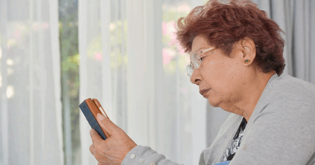 高齢入居者がスマートフォンを操作しながら見守りサービスの利用方法を確認している様子