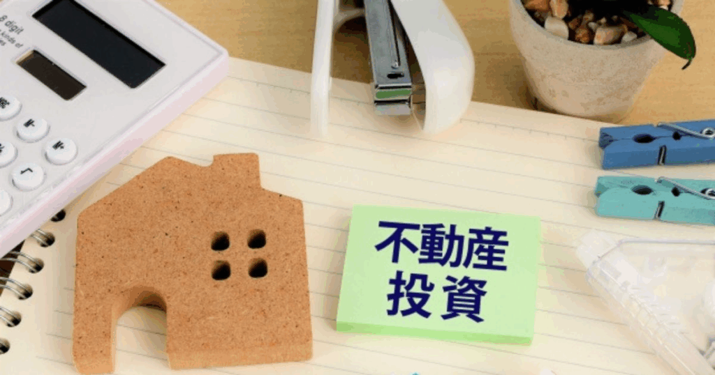 不動産投資を象徴するイメージ写真 不動産投資をイメージした写真|家の模型とメモ、電卓のあるデスク
