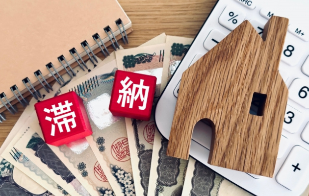 ノートと現金、電卓の上に赤い積み木で「滞納」と書いてある写真